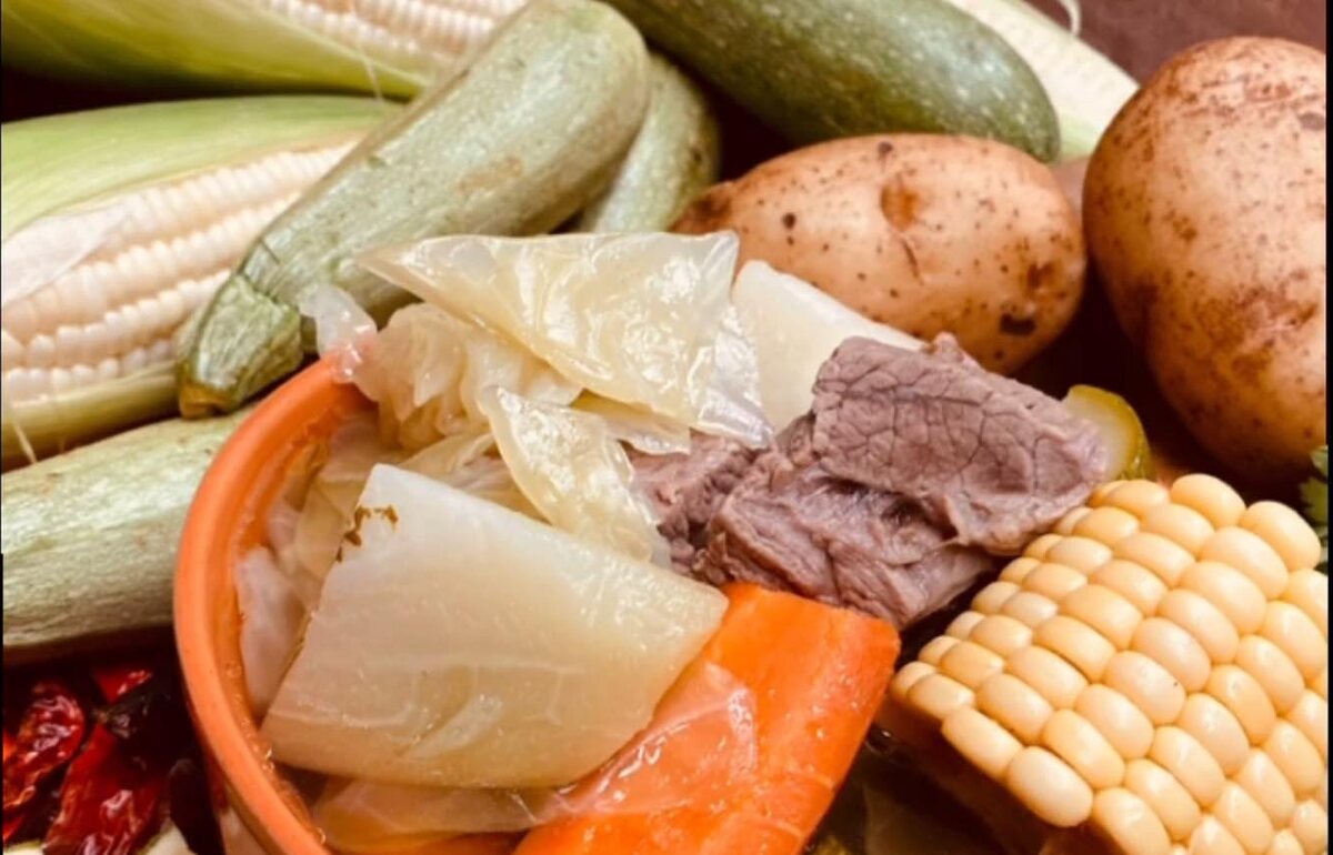 A caldo with corn, squash, potato, cabbage and beef in a clay bowl